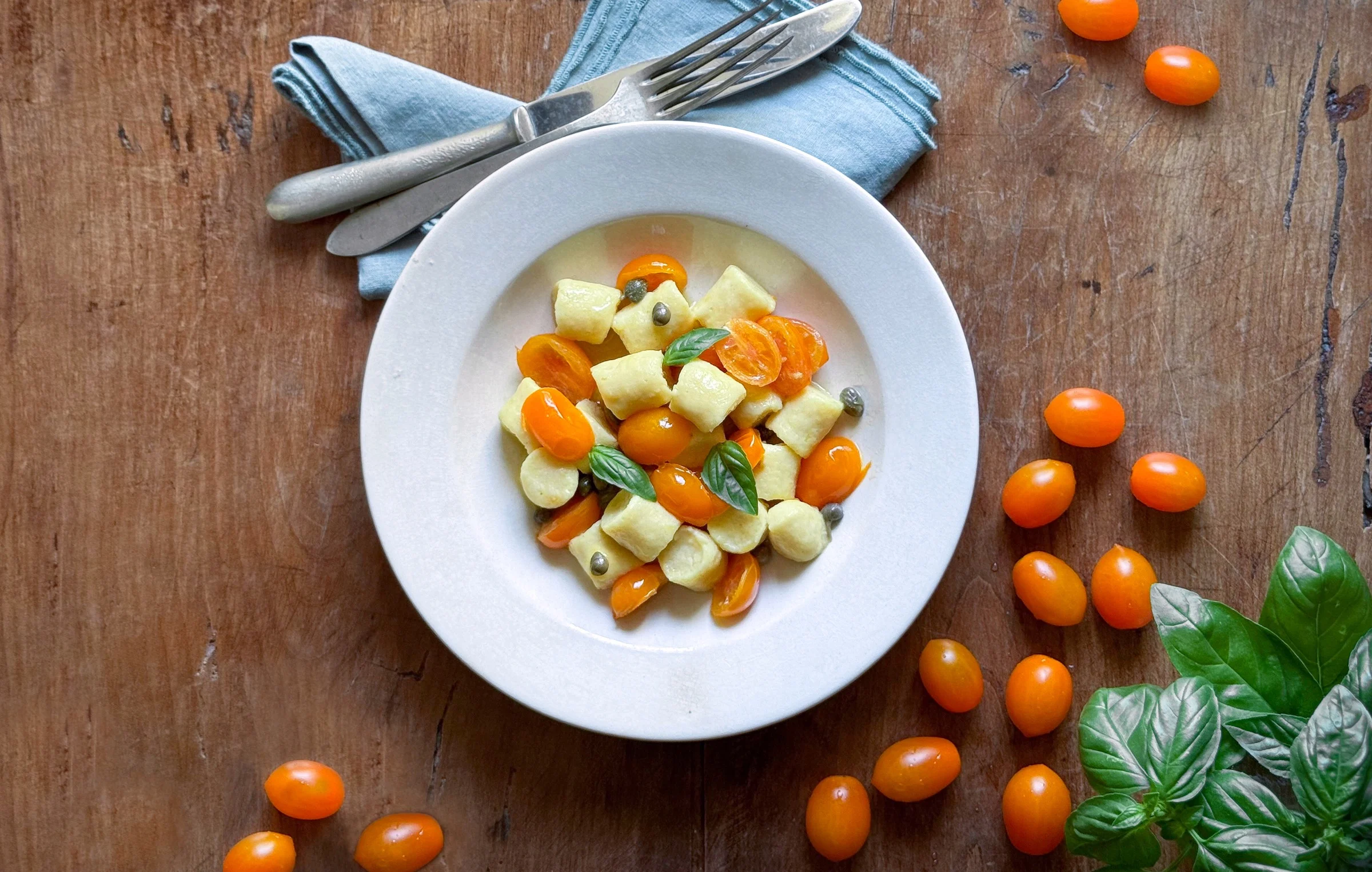 Ñoquis de ricotta con tomate datterino amarillo, alcaparras y albahaca
